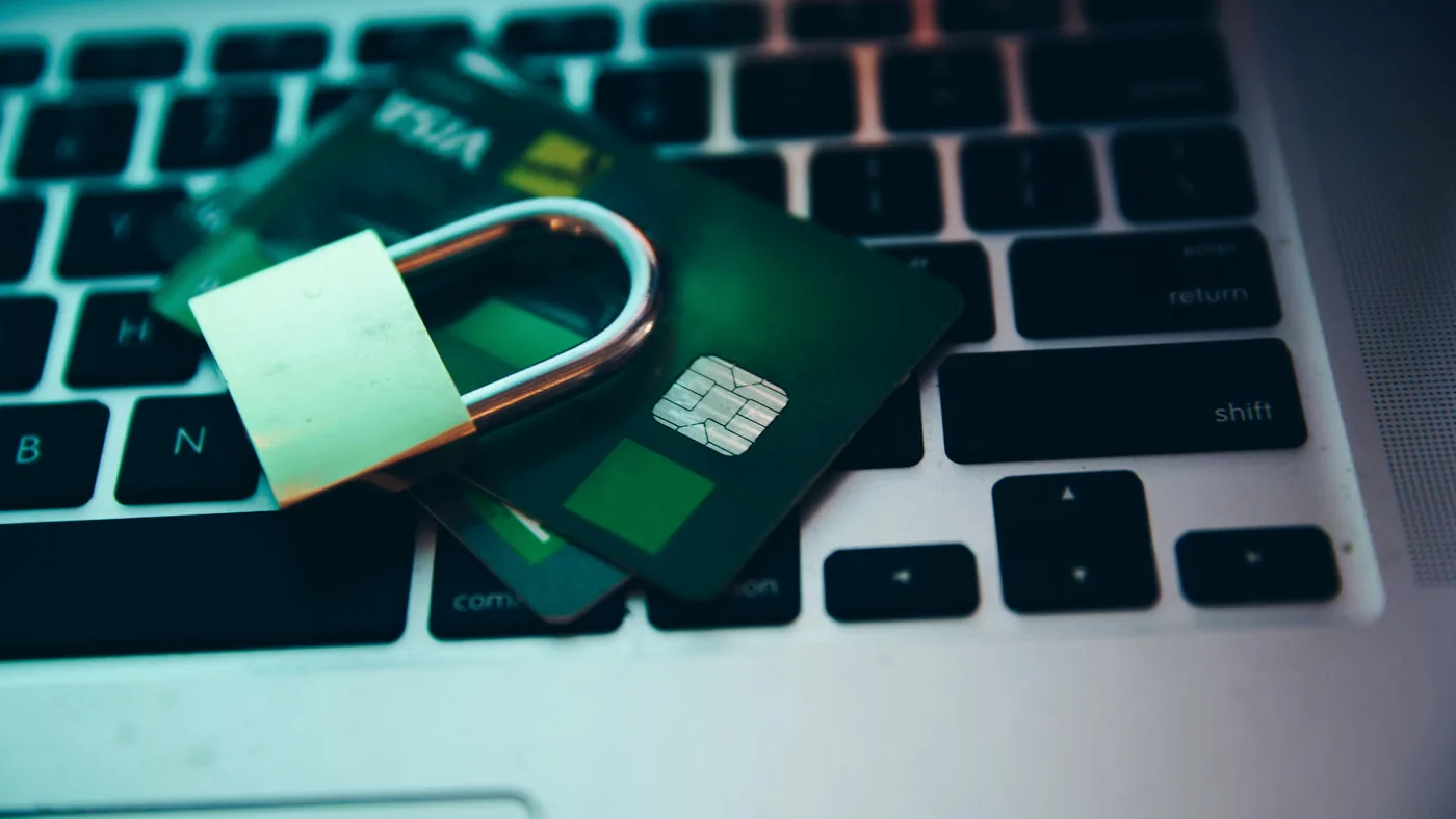 A padlock and payment card on a laptop keyboard representing digital lock security